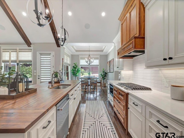kitchen featuring appliances with stainless steel finishes, dark wood finished floors, a sink, an inviting chandelier, and wood counters
