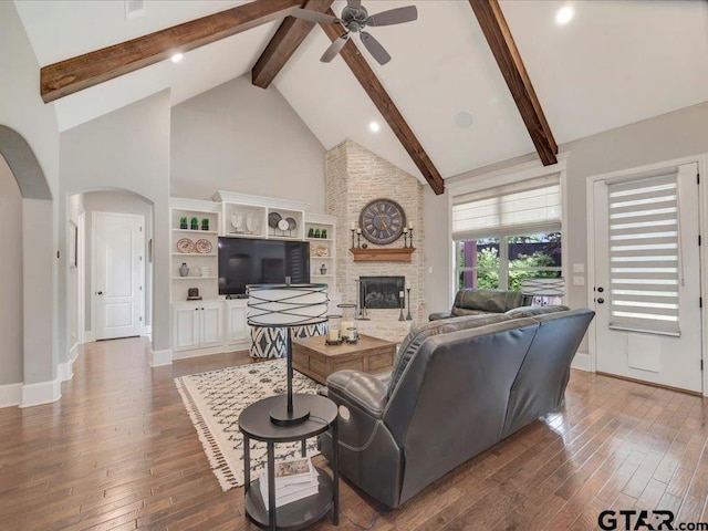 living room featuring arched walkways, ceiling fan, beam ceiling, and hardwood / wood-style floors