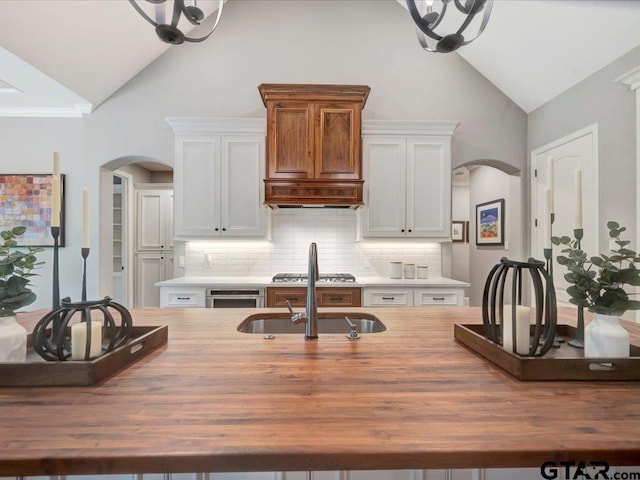 kitchen featuring arched walkways, decorative backsplash, and butcher block counters