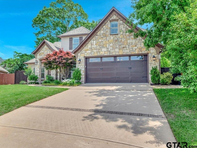 craftsman inspired home featuring fence, an attached garage, a front lawn, stone siding, and driveway