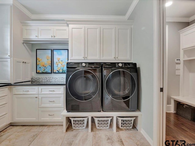 laundry room featuring washing machine and clothes dryer, crown molding, and cabinet space