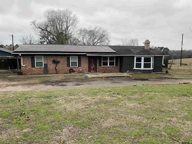 ranch-style house with a front yard and solar panels