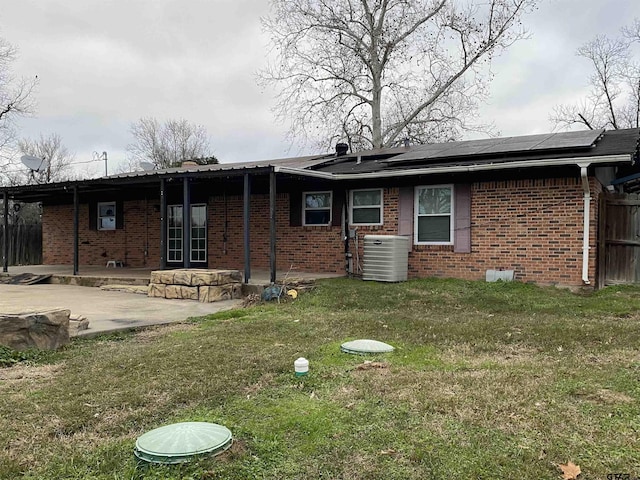 back of property featuring central AC unit, a yard, a patio area, and solar panels