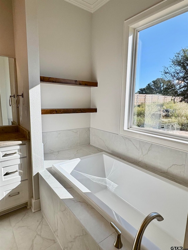 bathroom with a relaxing tiled tub, vanity, and ornamental molding