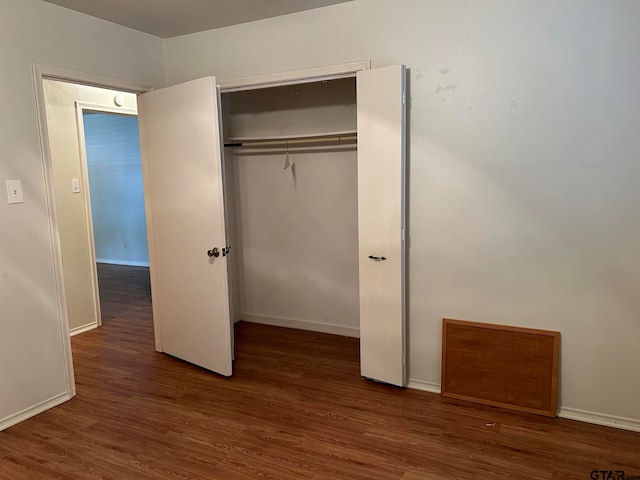 unfurnished bedroom with dark wood-type flooring and a closet