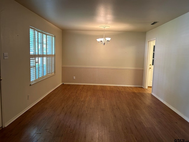 empty room featuring a chandelier and dark hardwood / wood-style flooring