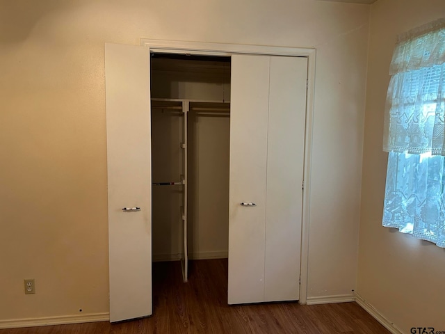 unfurnished bedroom with dark hardwood / wood-style flooring and a closet