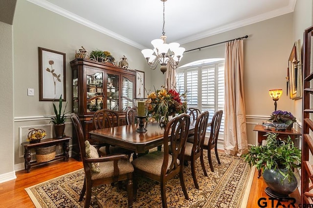 dining room featuring a chandelier, light hardwood / wood-style flooring, and ornamental molding