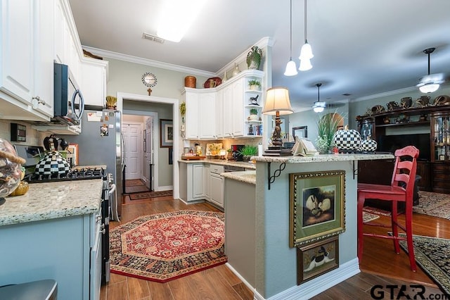 kitchen with dark hardwood / wood-style flooring, white cabinets, a kitchen breakfast bar, pendant lighting, and appliances with stainless steel finishes