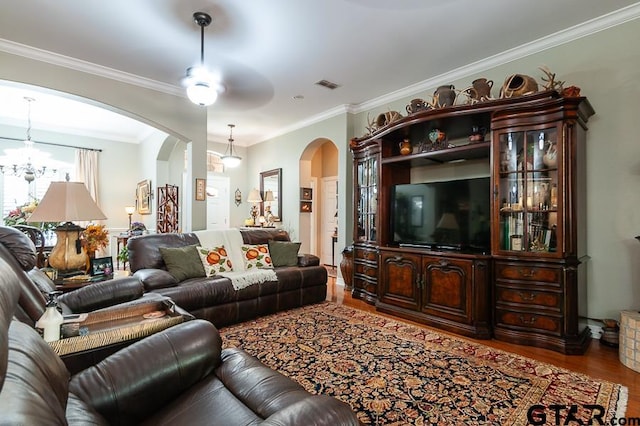 living room with ornamental molding, ceiling fan with notable chandelier, and hardwood / wood-style flooring