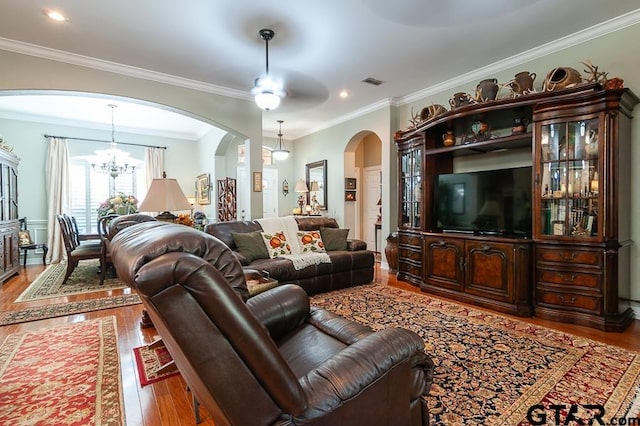 living room featuring wood-type flooring, ceiling fan with notable chandelier, and crown molding