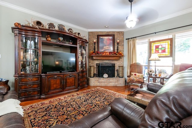 living room featuring a brick fireplace, hardwood / wood-style floors, ceiling fan, and crown molding