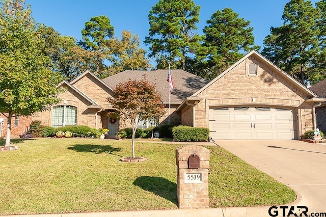 view of front facade featuring a front yard, concrete driveway, brick siding, and an attached garage