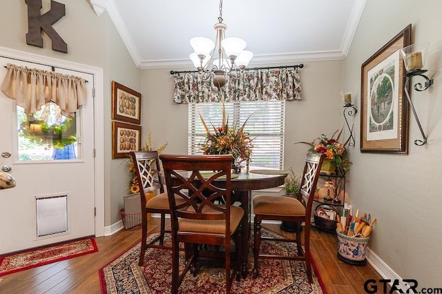 dining space with lofted ceiling, wood-type flooring, an inviting chandelier, and crown molding