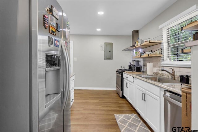 107 W Nutbush, Tyler, TX 75702 - kitchen featuring appliances with stainless steel finishes, open shelves, electric panel, light wood-style floors, and backsplash