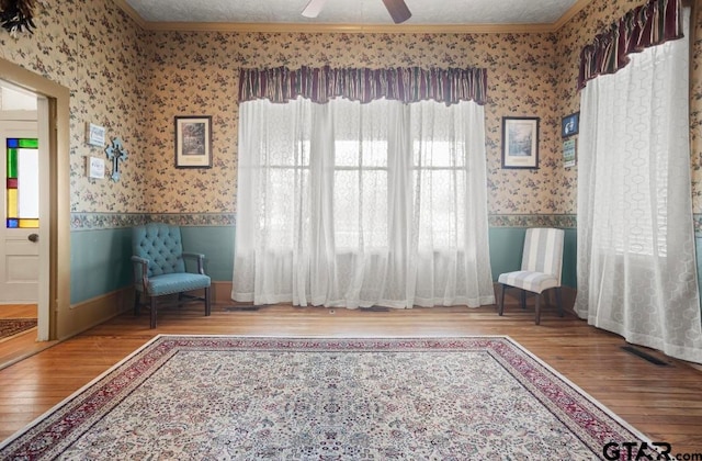 unfurnished room with ceiling fan, wood-type flooring, a textured ceiling, and ornamental molding