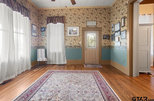 foyer entrance with ornamental molding, a textured ceiling, ceiling fan, wood-type flooring, and plenty of natural light