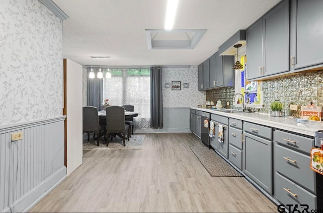 kitchen with gray cabinetry, sink, decorative light fixtures, light hardwood / wood-style flooring, and dishwasher