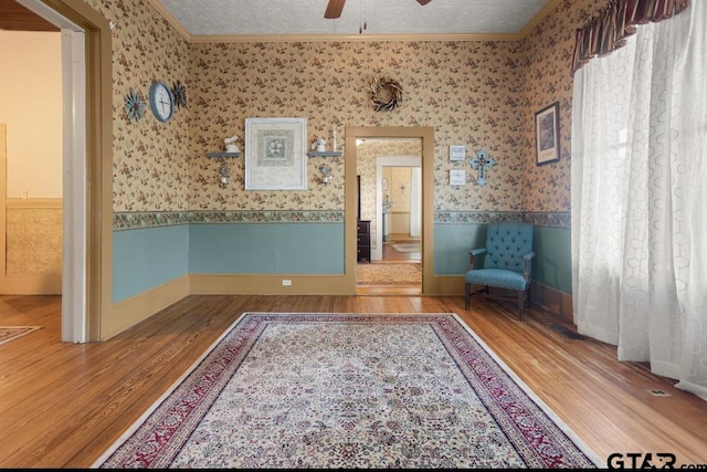 unfurnished room with a textured ceiling, hardwood / wood-style flooring, ceiling fan, and crown molding