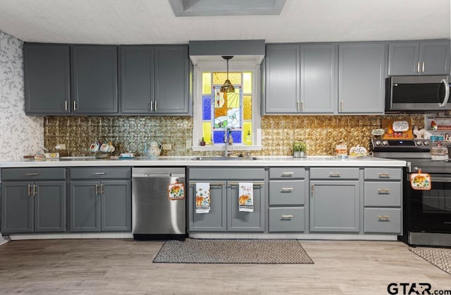 kitchen featuring appliances with stainless steel finishes, light wood-type flooring, gray cabinetry, and sink