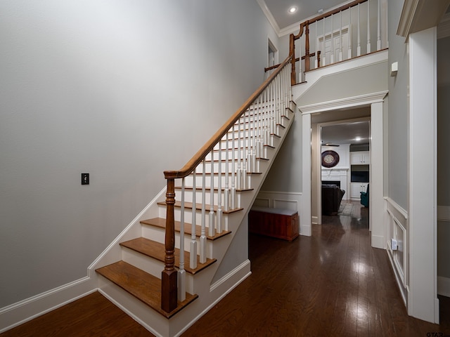 stairs featuring crown molding, baseboards, wood finished floors, and a fireplace