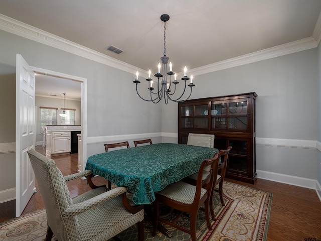 dining space featuring dark wood-style flooring, visible vents, baseboards, a notable chandelier, and ornamental molding