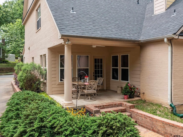 back of property with brick siding, a patio area, and roof with shingles