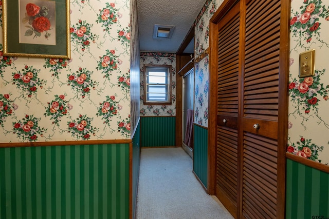 corridor with carpet floors and a textured ceiling