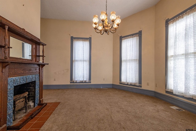 unfurnished living room with a textured ceiling, a fireplace, a healthy amount of sunlight, and dark carpet