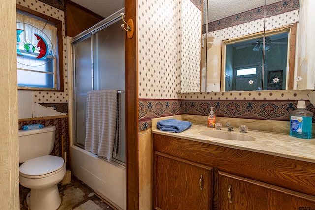 full bathroom featuring toilet, vanity, a textured ceiling, and shower / bath combination with glass door