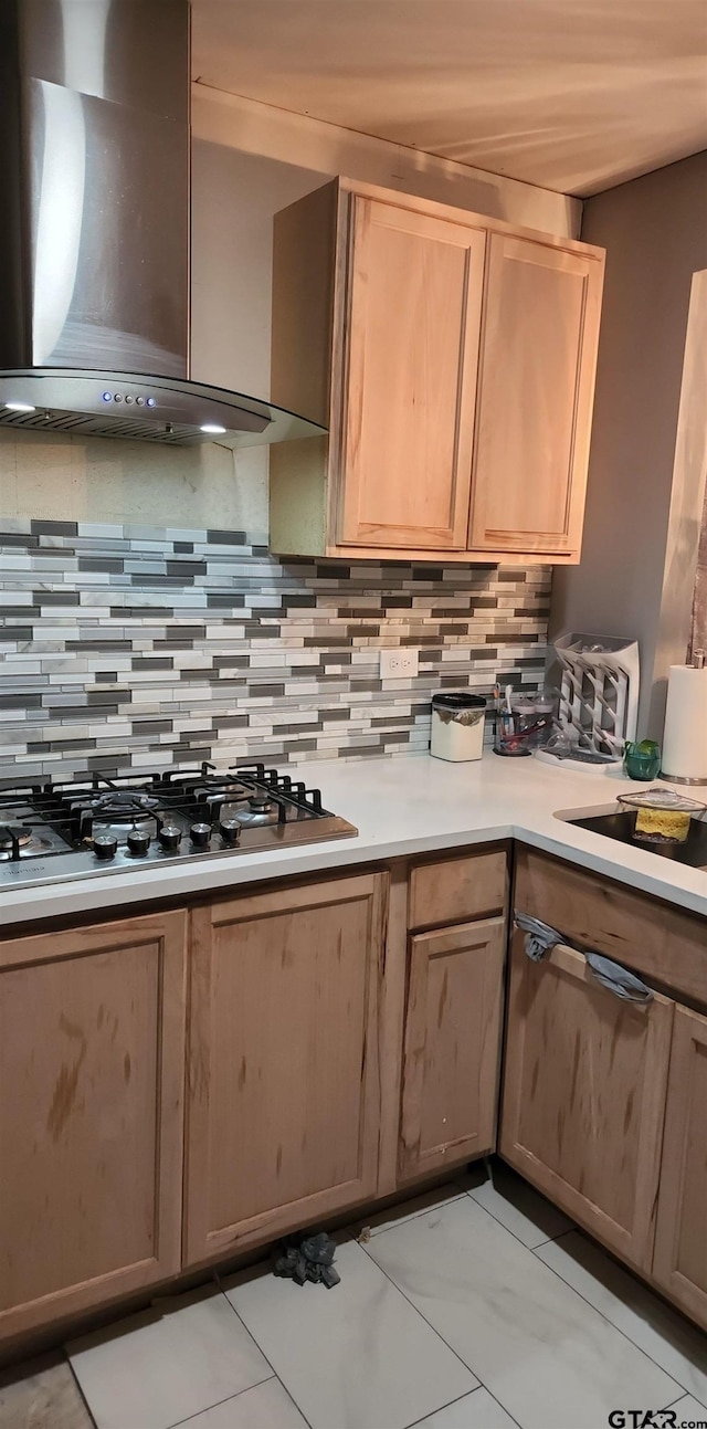 kitchen with backsplash, light brown cabinetry, wall chimney exhaust hood, and stainless steel gas stovetop