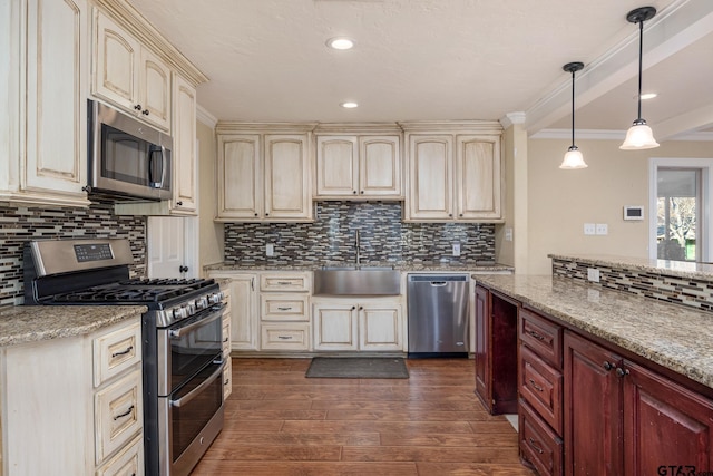 kitchen featuring appliances with stainless steel finishes, sink, hanging light fixtures, and cream cabinetry