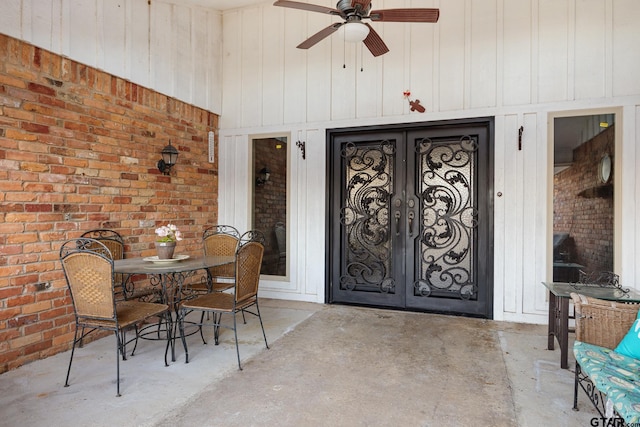 dining room featuring french doors, ceiling fan, brick wall, and wood walls