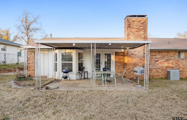 rear view of property with a lawn, cooling unit, french doors, and a patio area