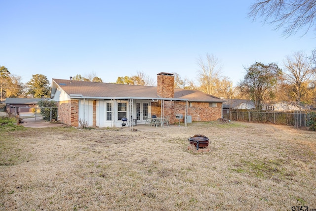 rear view of property featuring a lawn and a fire pit