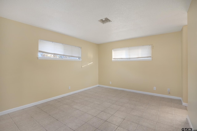 empty room with light tile patterned floors and a textured ceiling