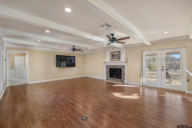 unfurnished living room featuring hardwood / wood-style floors, beam ceiling, and a textured ceiling