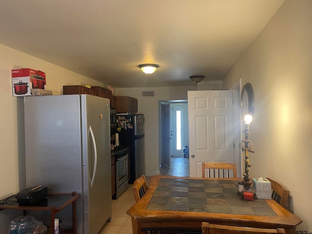 kitchen with stainless steel appliances, tile countertops, and light tile patterned flooring