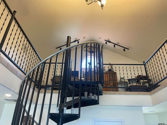 stairway featuring rail lighting and vaulted ceiling