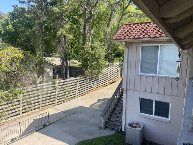 464 Forest Hills Dr, Livingston, TX 77351 - view of property exterior with central AC unit, a tiled roof, stairway, board and batten siding, and a patio