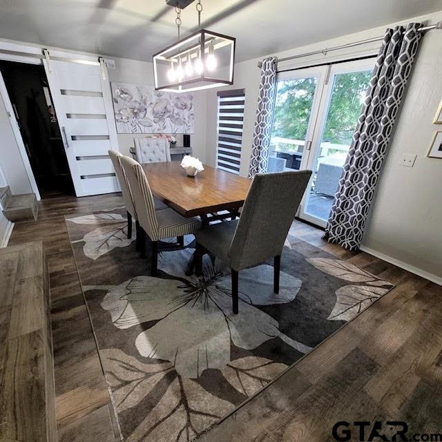 dining space featuring a barn door and dark hardwood / wood-style flooring