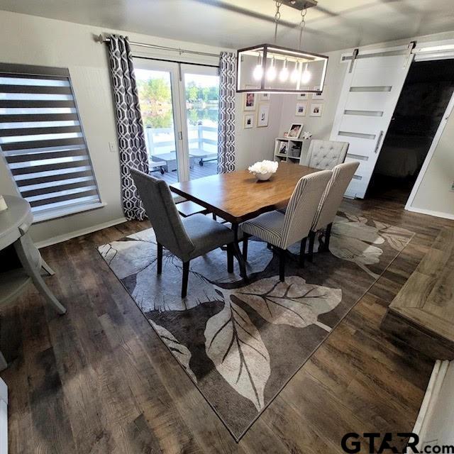 dining room with dark wood-type flooring and a barn door