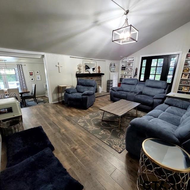 living room featuring hardwood / wood-style flooring, a healthy amount of sunlight, lofted ceiling, and a notable chandelier