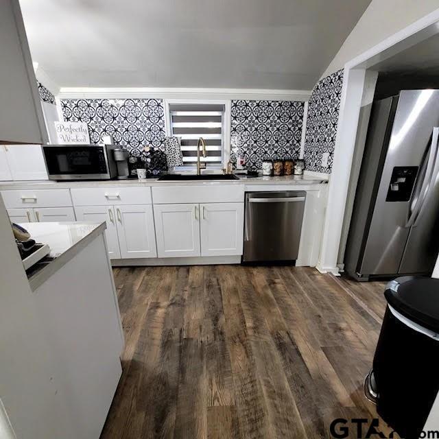 kitchen featuring white cabinetry, sink, appliances with stainless steel finishes, dark hardwood / wood-style floors, and backsplash