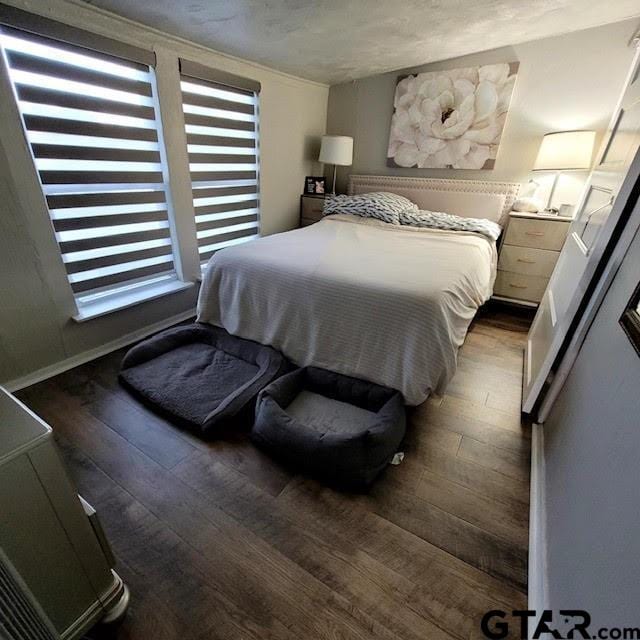 bedroom featuring a textured ceiling and dark hardwood / wood-style flooring