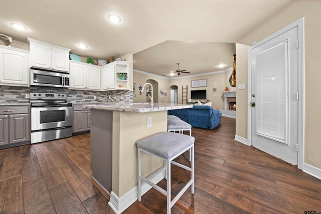 kitchen featuring stainless steel appliances, a kitchen bar, white cabinetry, and dark hardwood / wood-style floors