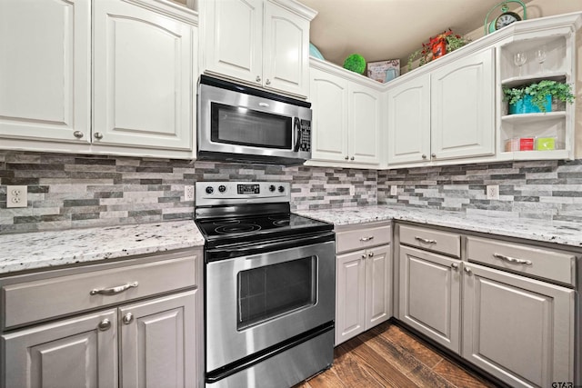 kitchen with white cabinetry, stainless steel appliances, dark wood-type flooring, and light stone counters