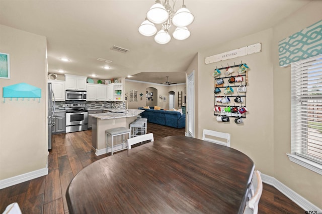 dining space featuring ceiling fan with notable chandelier, dark wood-type flooring, and sink