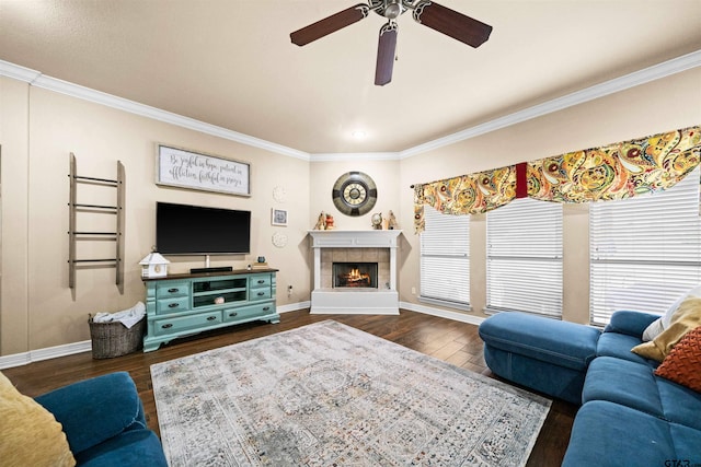 living room with ornamental molding, dark wood-type flooring, ceiling fan, and a tile fireplace