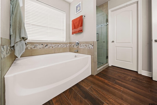 bathroom featuring wood-type flooring and shower with separate bathtub